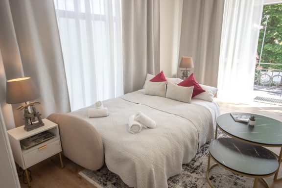 Helles Schlafzimmer mit einem Bett, eleganten Kissen und einem kleinen Tisch.
