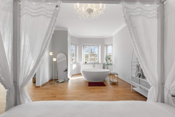 Heller, eleganter Raum mit freistehender Badewanne und großen Fenstern.
