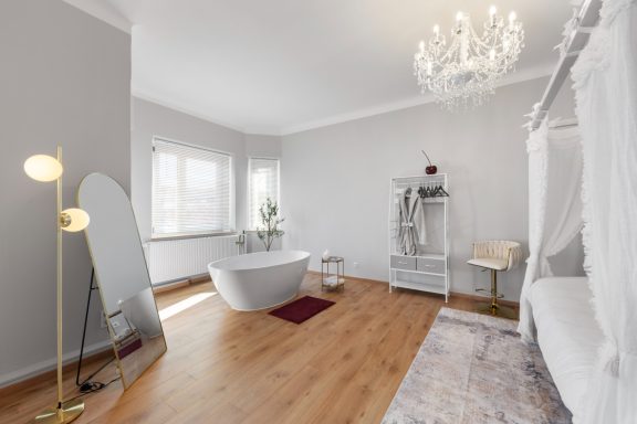 Modernes Badezimmer mit freistehender Badewanne, eleganter Lampe und hellem Interieur.